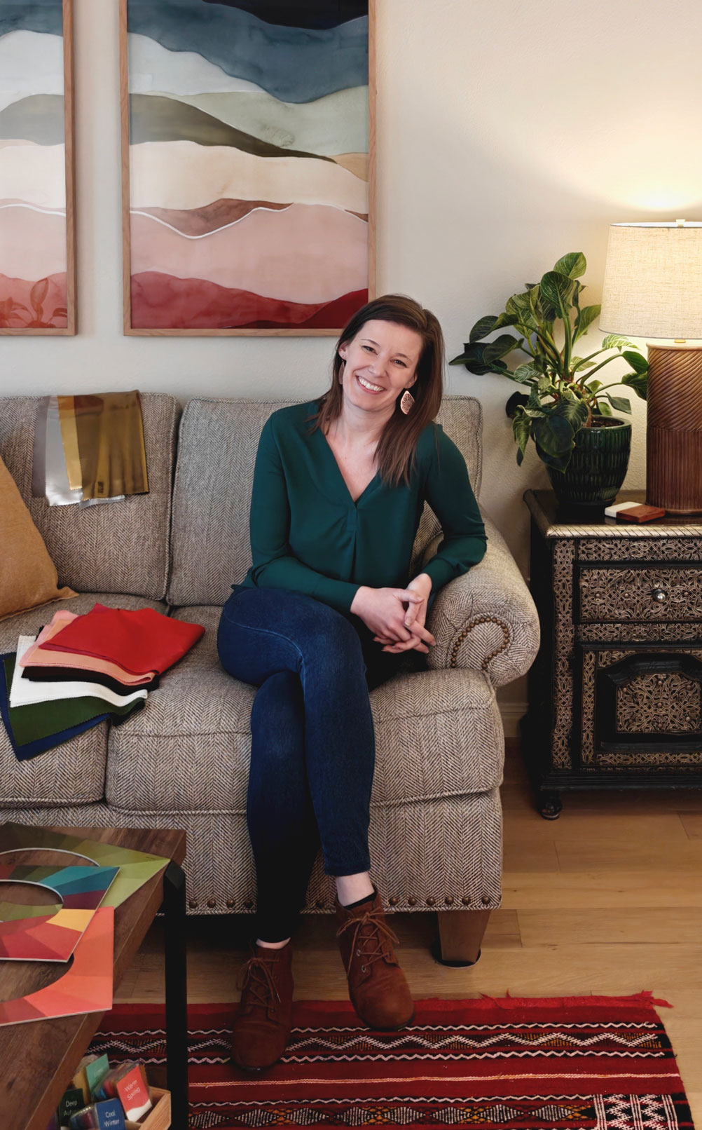 Hannah seated in the studio on a couch beside color drapes