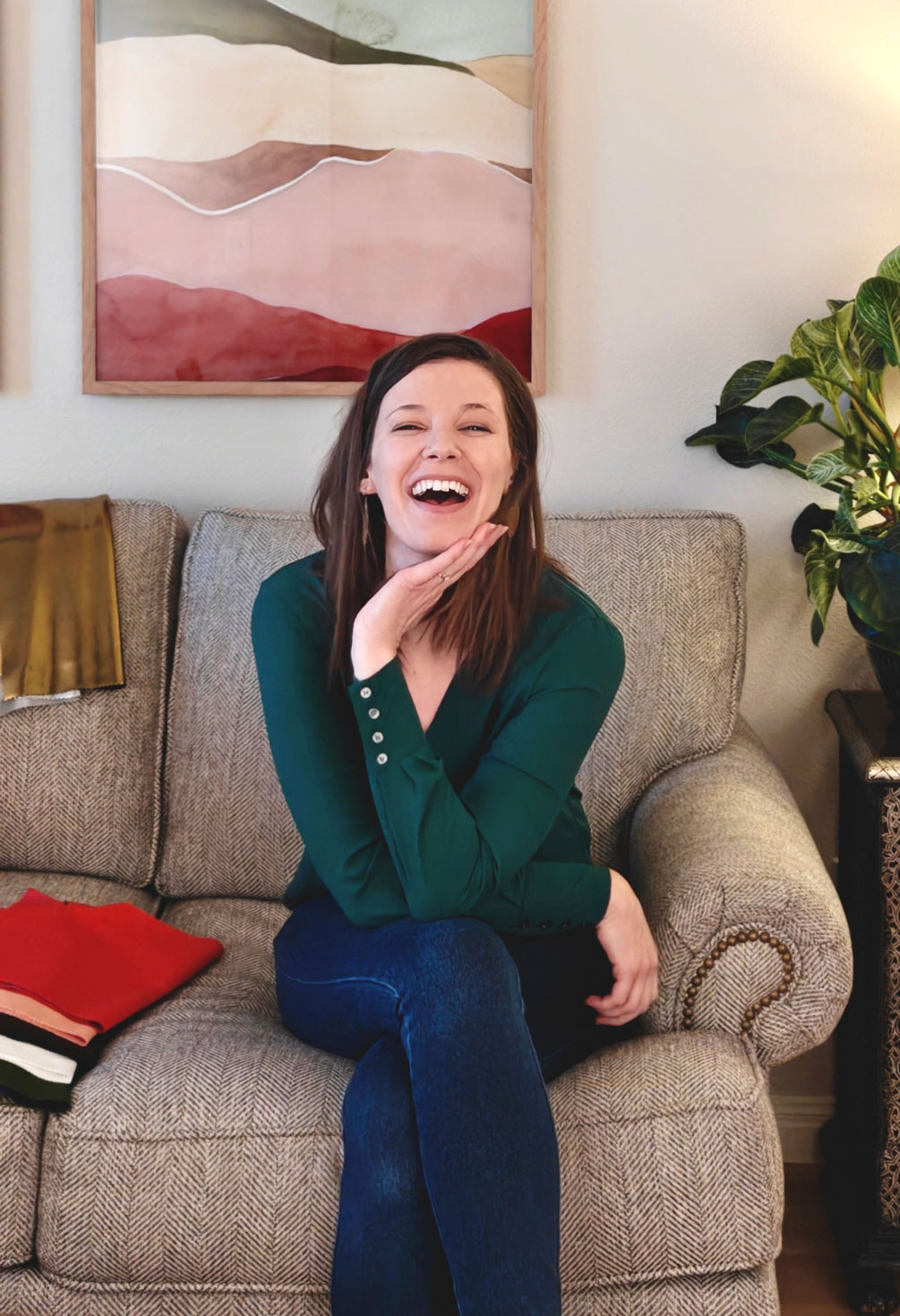 Hannah smiling in the studio seated on a couch